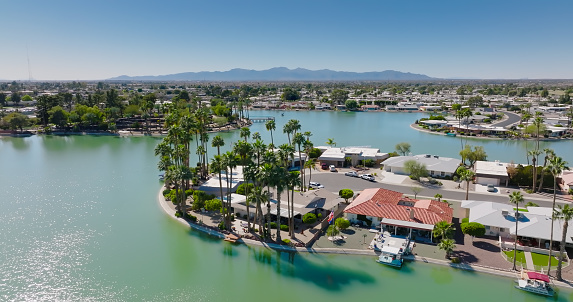 Aerial shot of houses built around an artificial lake in Sun City, an age restricted community in the metropolitan area of Phoenix,  Arizona on a clear sunny day.