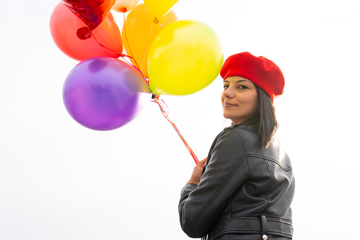 Young woman holding bunch of colorful balloons