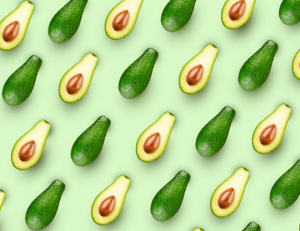 istock Wholes and halves avocados  in seamless pattern on green background. Excellent retouching quality. Top view, flat lay 1397610231