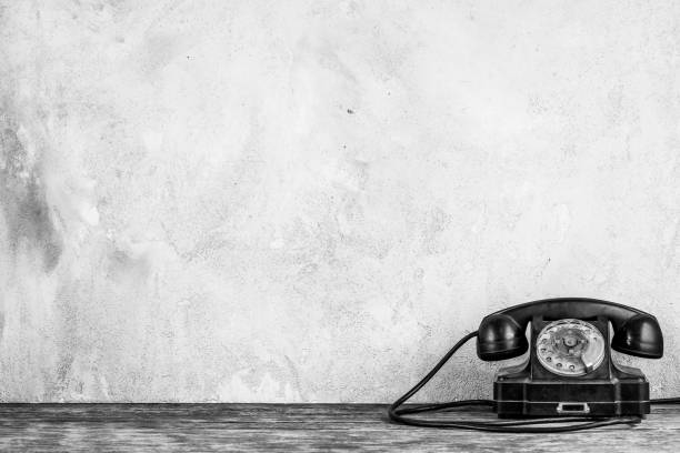 istock Retro black rotary telephone on wooden table in front gray concrete background 1397611347