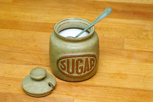 Sugar jar with spoon on wooden worktop