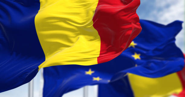 detail of the national flag of romania waving in the wind with blurred european union flag - romania flag romanian flag colors imagens e fotografias de stock