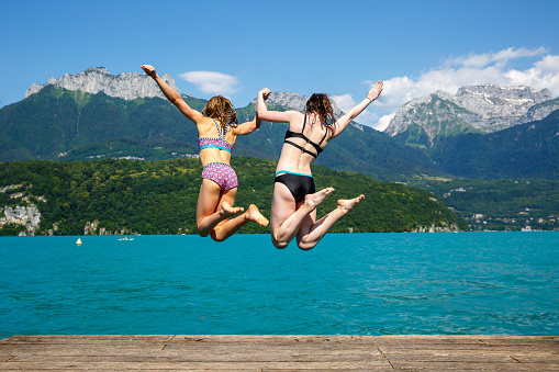 Two teen girls jumping into Lake Annecy at Plages de Saint Jorioz - France