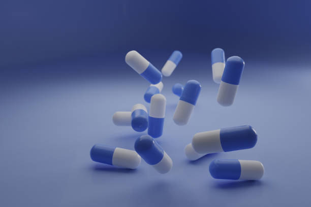 A group of antibiotic pill falling on a blue background. Healthcare and medical 3D concept. stock photo