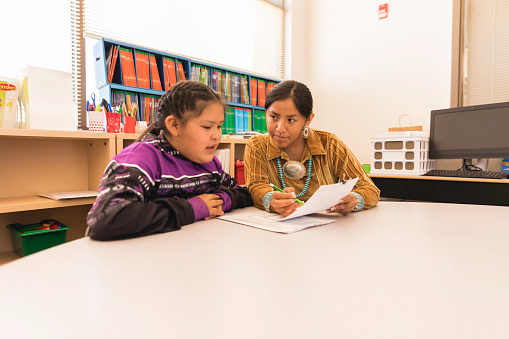 An Navajo Elementary school teacher is taking the time to explain a difficult concept and subject to a student. Image taken on the Navajo Reservation, Utah.