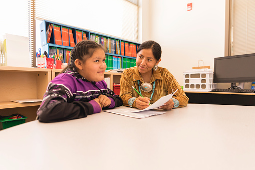 An Navajo Elementary school teacher is taking the time to explain a difficult concept and subject to a student. Image taken on the Navajo Reservation, Utah.
