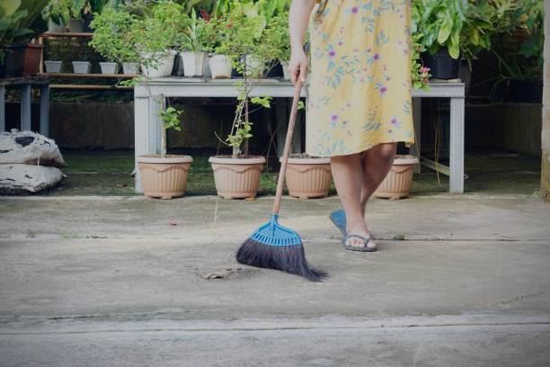 istock Female worker sweeping yard with broom  in yard garden 1397620980