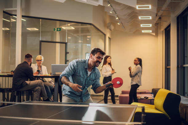 Young people playing table tennis in the office at work