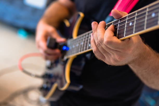 fotografia incentrata sulla mano sinistra di un uomo anonimo che suona la chitarra elettrica con l'ebow nel suo studio di casa - ebow foto e immagini stock