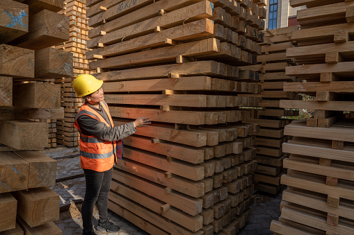 A Chinese female worker counts the quantity of wood in the wood warehouse