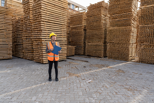 An Asian female warehouse worker works in the wood stacking area