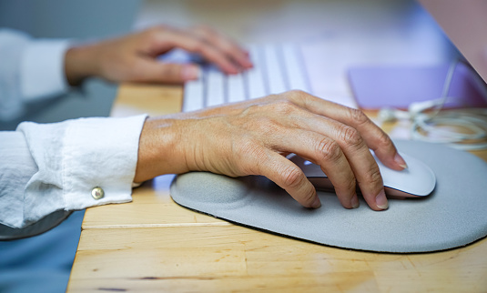 Woman's fingers clicking on mouse, resting her wrist on wrist rest. Close up view.