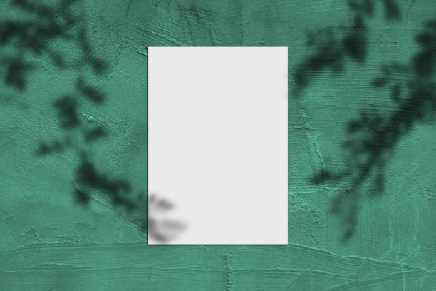 istock Blank white vertical rectangle poster mockup with light shadow on green concrete wall background. 1397632169