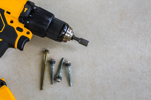 Cordless Hammer Drill and Screwdriver with screw on Cement board background