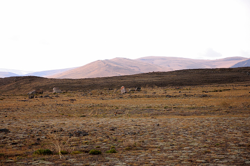 Ancient stone burials in the autumn desert steppe at the foot of the mountain range. Chui steppe, Altai, Siberia, Russia.