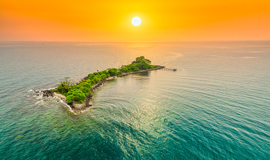 Vista aérea de una isla desierta en un fondo de agua turquesa y cielo al atardecer photo