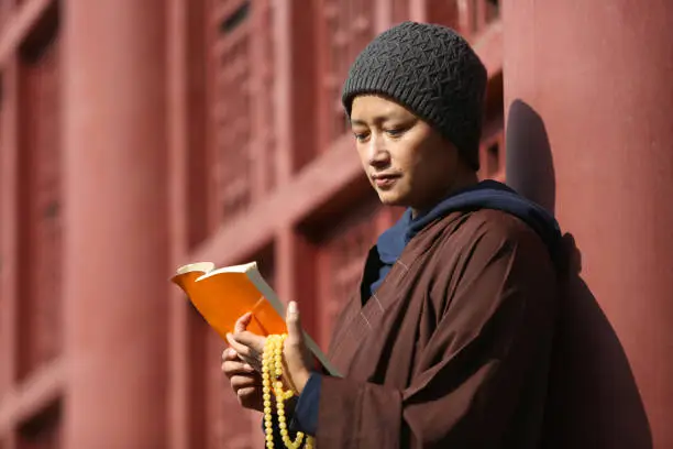A Chinese Nun Reading a book in a temple