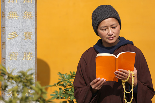 A Chinese Nun Reading a book in a temple