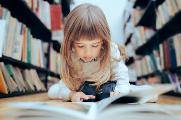 niña inteligente revisando un libro en la biblioteca - curiosity searching discovery home interior fotografías e imágenes de stock