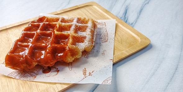 Croffle or Croissant  Waffle with Thai tea (orange-brown cream sauce) on wooden plate