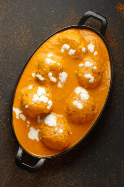 Malai Kofta Curry in black bowl. Malai Kofta is indian cuisine dish with potato and paneer cheese deep fried balls in onion tomato gravy with spices. Indian Food.