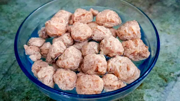 A Glycine max or Soya bean or uncooked soybean chunks soak in water. Served in a bowl or as a Pile. selective focus