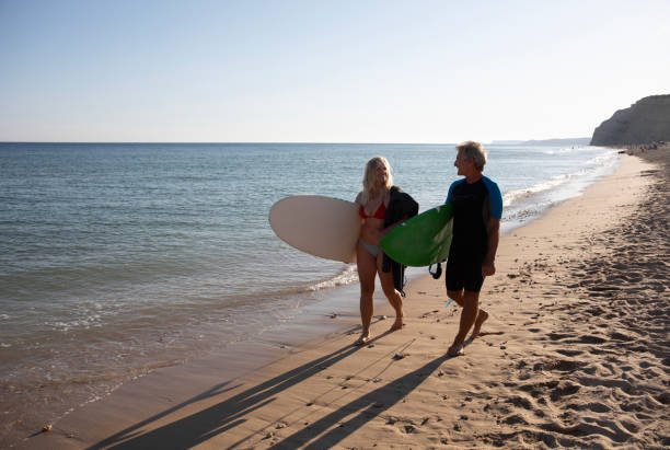 istock Couple carry surfboards along empty beach 1397652593