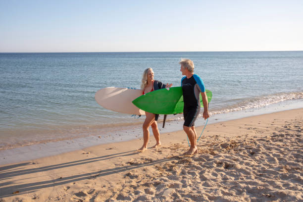 istock Couple carry surfboards along empty beach 1397652739