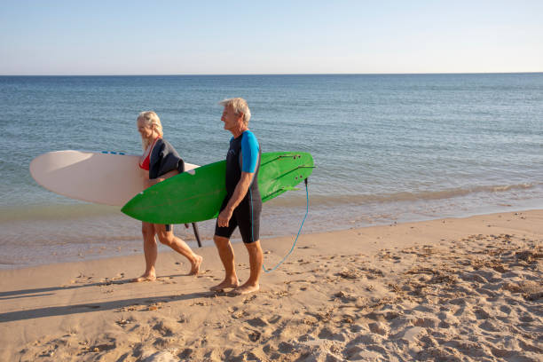 istock Couple carry surfboards along empty beach 1397652772