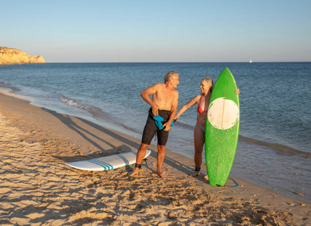 istock Couple prepare to surf at edge of empty beach 1397653703