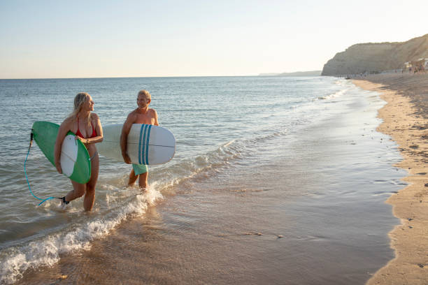 istock Couple carry surfboards from tranquil sea 1397654280