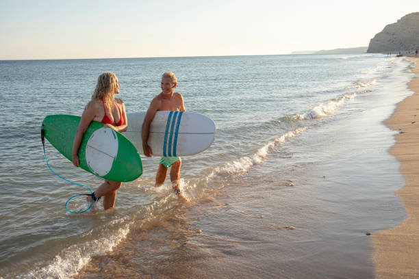 istock Couple carry surfboards from tranquil sea 1397654299
