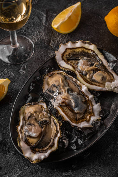 istock Fresh oysters close-up on ice served with lemon and wine. 1397654688