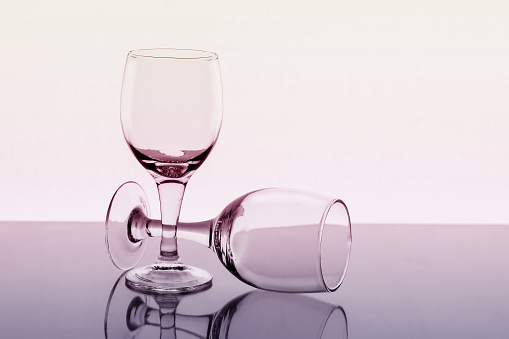 Two empty wine glasses with reflection on background, toned.