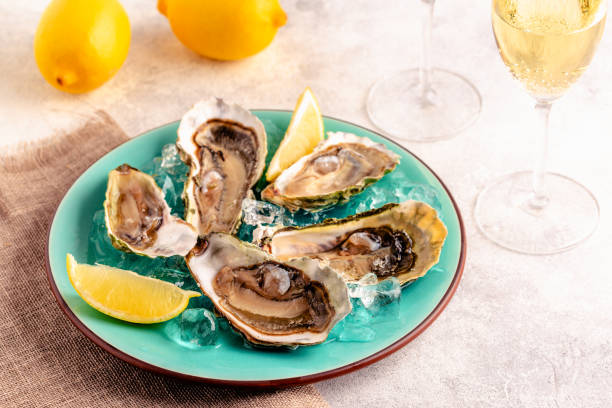 istock Opened fresh oysters on a blue plate, served with lemon and ice. 1397656256