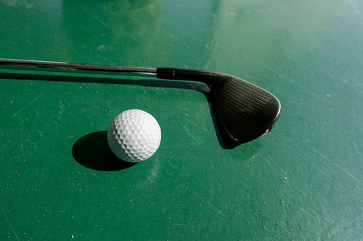 A golf club and a golf ball on the green