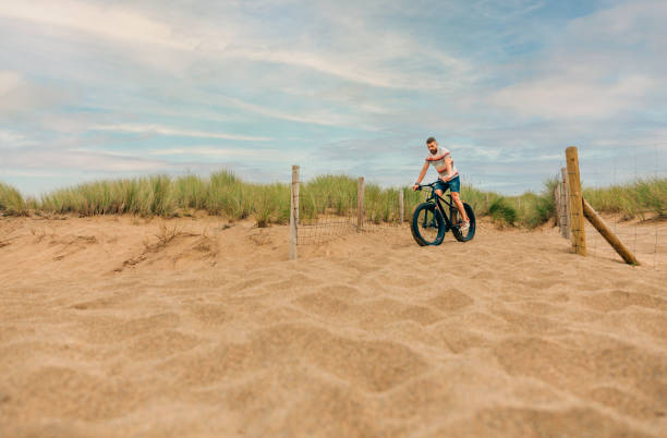 istock Man riding a fat bike through the beach dunes 1397661046