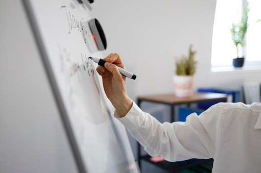 Woman hand with marker writing on white magnetic board