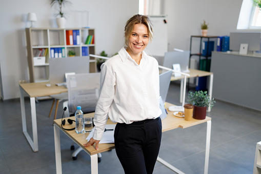 Business woman leaning against her desk in office