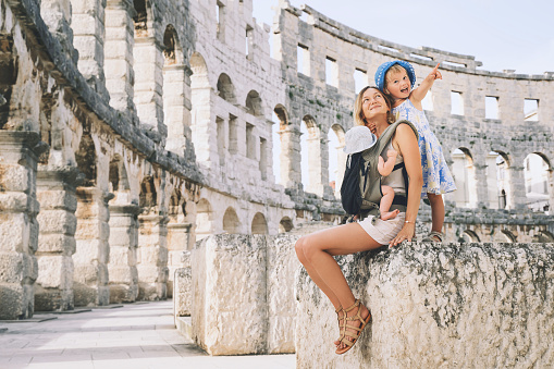 Tourist woman with small kids in Roman Amphitheater Arena like as Coliseum - famous travel destination in Pula, Croatia. Happy mother and children on vacation in Europe. Family Active Travel.