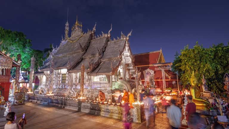 People walk with lighted candles in hand around a temple in Visakha Bucha day at Sri Suphan Temple Chiang mai