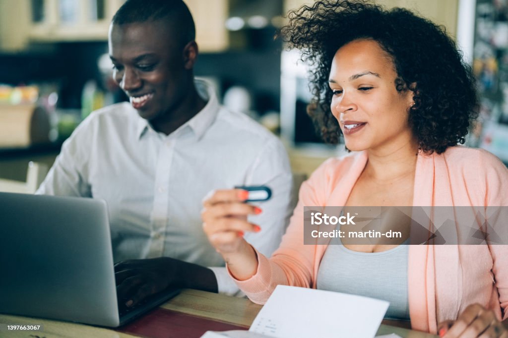 Woman with her husband paying bills from home Mixed race family paying bills from home Digital Authentication Stock Photo