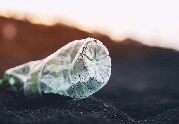 Plastic bottle on black sand on beach. Plastic pollution in ocean. Environment concept. Garbage collected on beach
