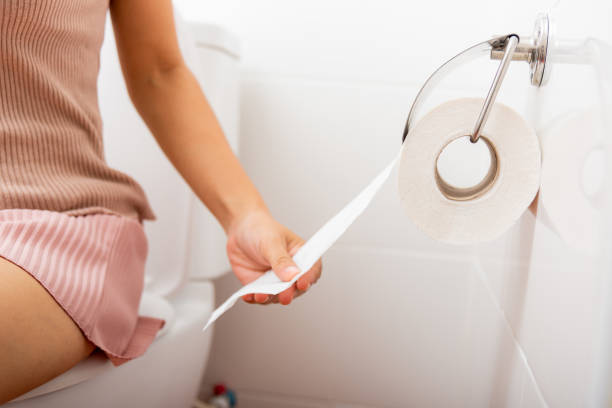 Closeup hand pulling toilet paper roll in holder for wipe	Closeup hand pulling toilet paper roll in holder for wipe, woman sitting on toilet she taking and tearing white tissue on wall to towel clean in bathroom, Healthcare concept Closeup hand pulling toilet paper roll in holder for wipe, woman sitting on toilet she taking and tearing white tissue on wall to towel clean in bathroom, Healthcare concept toilet stock pictures, royalty-free photos & images