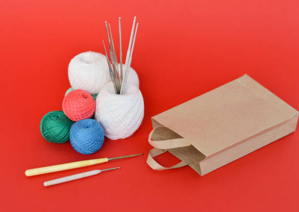 A closeup shot of red, purple, and blue knitting yarns and crochet hooks A closeup shot of red, purple, white and blue knitting yarns and crochet hooks with paper bag for purchase, sale. hook equipment stock pictures, royalty-free photos & images