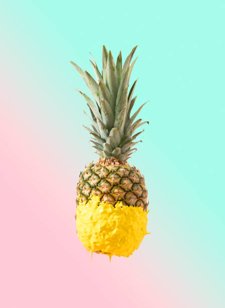 istock Creative Summer pineapple fruit dripped in yellow paint. Tasty refreshing snack for beach party. Pastel pink and blue background. 1397665586