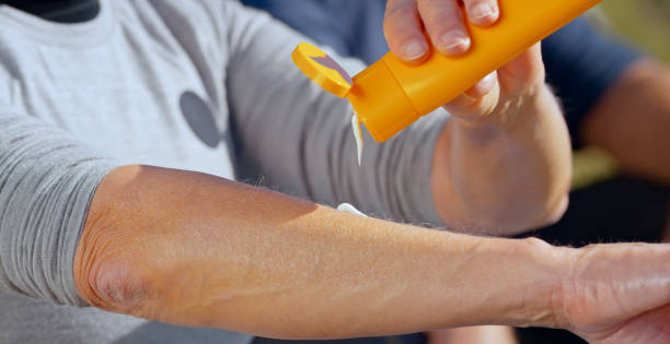 Woman pouring cream on hand Senior woman sitting on mountain and taking break while applying sun cream on hand. suntan lotion stock pictures, royalty-free photos & images