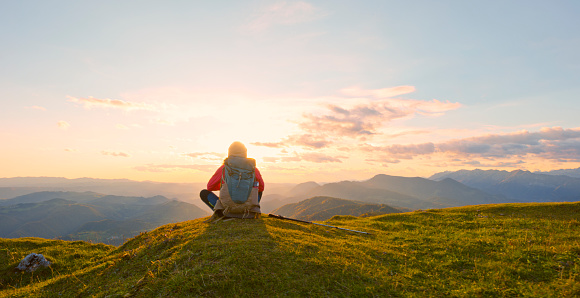 Rear view of mature woman mediating after hiking while sitting on top of mountain.