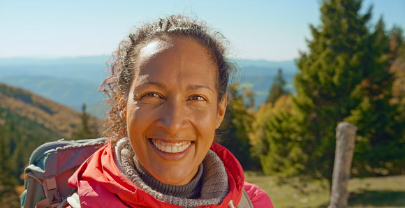 Portrait of smiling hiker mature woman against sky.