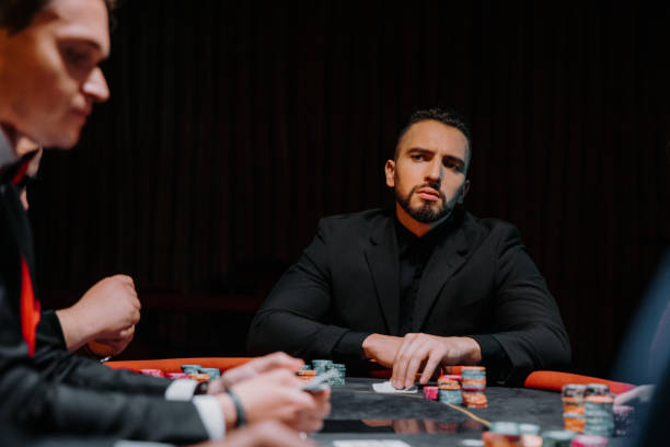 A group of male and female evening dress players sit at a gaming table with gaming chips. A group of male and female evening dress players sit at a gaming table with gaming chips. child gambling chip gambling poker stock pictures, royalty-free photos & images